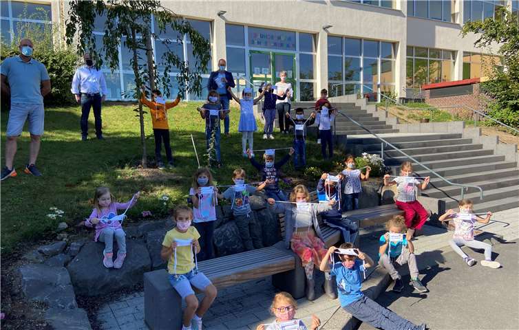 Bürgermeister Lempertz (hinten Mitte) freut sich mit Teilbereichsleiter Herr Wittig (oben Mitte links) die neuen Masken der Verbandsgemeinde Mendig an die Schüler und Schulleiterin Frau Pretz (oben rechts) und Konrektor Herr Busch (oben links) zu überreichen. Foto: VG Mendig