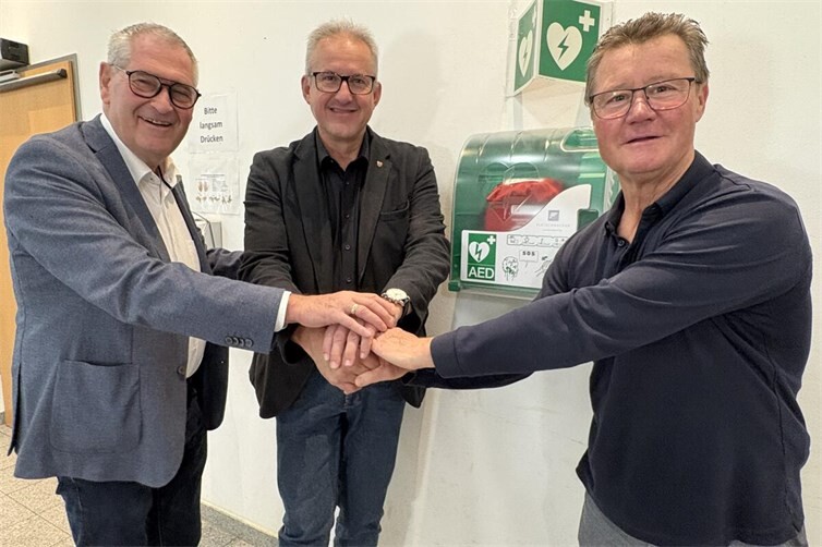 Bürgermeister Matthias Renschler (Mitte) bei der Übergabe der AED-Defibrillatoren mit dem Ersten Beigeordneten Peter Diewald (links) und Ortsvorsteher Richard Lindner