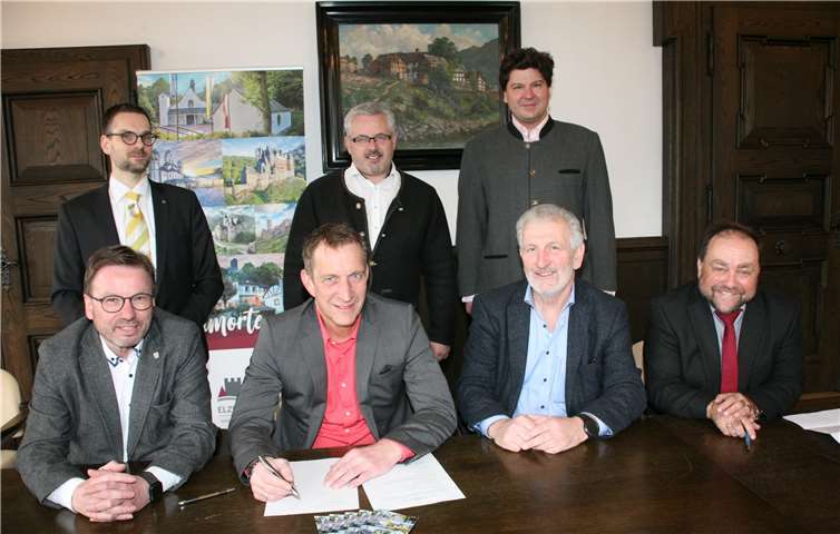 Bürgermeister Maximilian Mumm unterzeichnet den Beitritt der Verbandsgemeinde Maifeld zur Kooperation Elzerland. Darüber freuen sich die bisherigen Partner (vorn von links) Oberbürgermeister Wolfgang Treis für die Stadt Mayen, Bürgermeister Bruno Seibeld für die Verbandsgemeinde Rhein-Mosel und Bürgermeister Alfred Schomisch für die Verbandsgemeinde Vordereifel sowie (hinten von links) Philipp Lohse für die Vereinigung der Benediktiner zu Maria Laach, Bürgermeister Albert Jung für die Verbandsgemeinde Kaisersesch und Jakob Graf zu Eltz für die Burg Eltz. Es fehlt die Vertreterin der Generaldirektion Kulturelles Erbe, die die erweiterte Kooperation später unterschreibt.Foto: WE