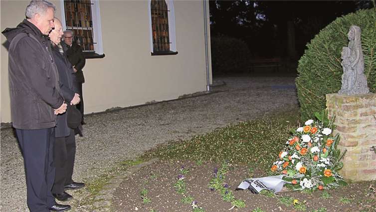Bürgermeister Stefan Raetz und Ehrenbürger Heinz Büttgenbach legen vor der Marien-Kapelle an der „Pietà“ von Pater Ludwig ein Gesteck nieder.