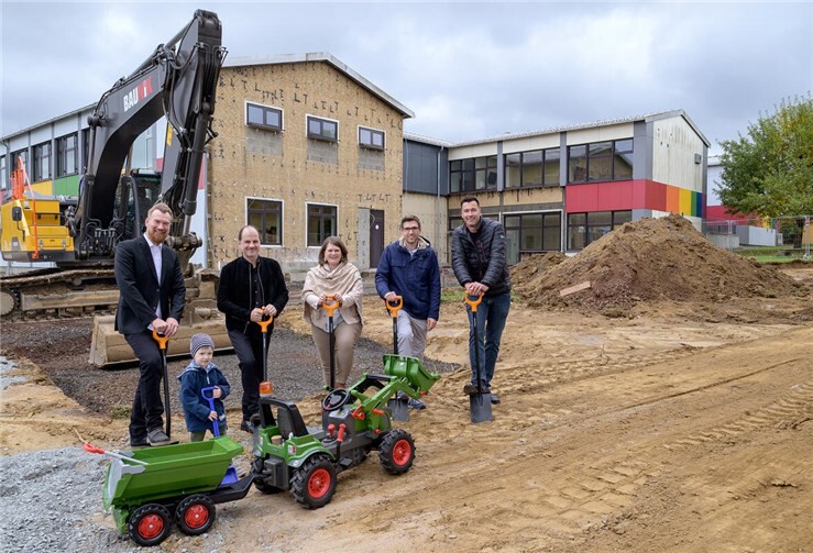 Bürgermeisterin Alexandra Marzi (Mitte), Dominik Fußhöller, Vertreter stv. Schulleitung Grundschule Dernbach (links im Bild), Architekt Michael Graf (2ter v. links) und Fachbereichsleiter Bauen, Klimaschutz und Immobilien der VG Wirges Martin Menges (2ter v. rechts) sowie Gruppenleiter Bauleitplanung und Immobilienmanagement Andreas Schwind setzten mit dem Spatenstich den offiziellen Startschuss für den Erweiterungsbau der Pfarrer-Giesendorf-Grundschule in Dernbach – begleitet von einem jungen Baustellenfan mit seinem Kipper. Foto: VG Wirges/ Silja Götte