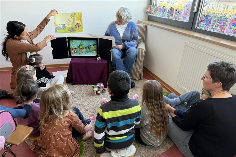 Bunter Vorlesespaß in Wirges: Andrea Berger (rechts) las den Kindern der Caritas-Kita Sankt Franziskus die Geschichte vom Elefanten Elmar vor. Unterstützt wurde sie dabei von Anke Meurer (links), die die Erzählung mit Bildern im Kamishibai-Erzähltheater begleitete. Foto: Holger Pöritzsch/Caritasverband WWRL