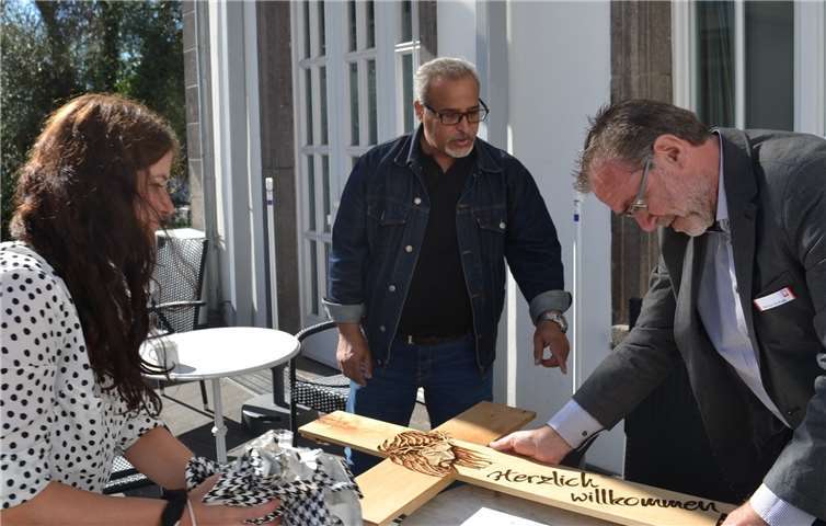 Carina Klee und Werner Steffens packen das Geschenk aus, während Mo.T (Mitte) erklärt, dass er das Kreuz mit Brandtechnik hergestellt hat.Foto: E.T. Müller