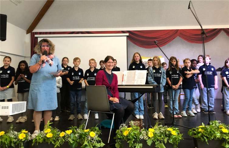 „Chorkids vom Ländchen“ mit links im blauen Kleid Rektorin Elke Weyers und Chorleiterin Daniela Bügler in der Mitte mit roter Jacke.