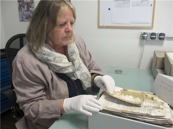 Christa Schäfer, Leiterin der Club Aktiv GmbH Akten- & Buch-Erhaltung, prüft die getrockneten Unterlagen aus dem Pfarrarchiv in Mettendorf. Foto: Stefan Schneider/Bistum Trier