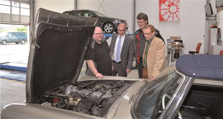 Christian Schwindt, Bürgermeister Bert Spilles, Michael Windeck und Wirtschaftsförderer Dirk Schwindenhammer (v.l.) werfen einen Blick in den Motorraum eines Oldtimers.  Stadt Meckenheim