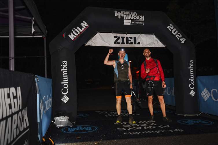 Claus Bünnagel (l.) aus Alteheck und Mitstreiter Adrian aus Kerpen um 4.30 Uhr im Ziel des Megamarschs Köln.. Foto: Sportograf.com