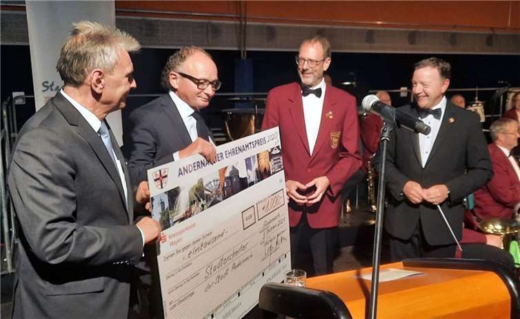 Claus Peitz und Achim Hütten überreichen den Ehrenamtspreis an die Orchesterleitung. Foto: privat