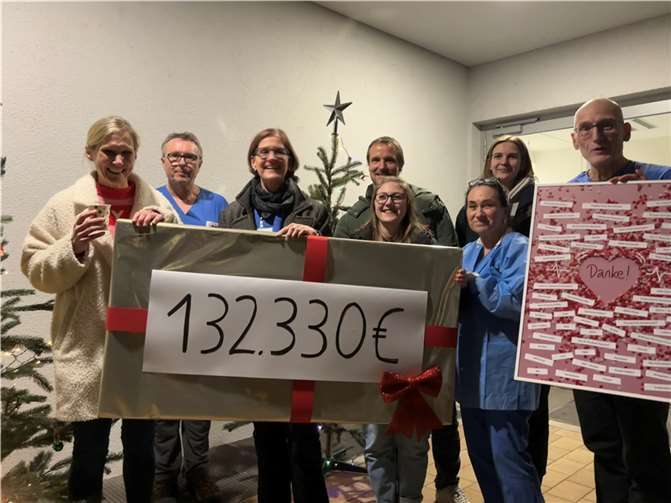 Corinna Gerhards (li.) übergibt dem Team der Kinderintensivstation und Chefarzt Thomas Nüßlein (re.) ein riesengroßes Weihnachtsgeschenk. Quelle: Corinna Gerhards