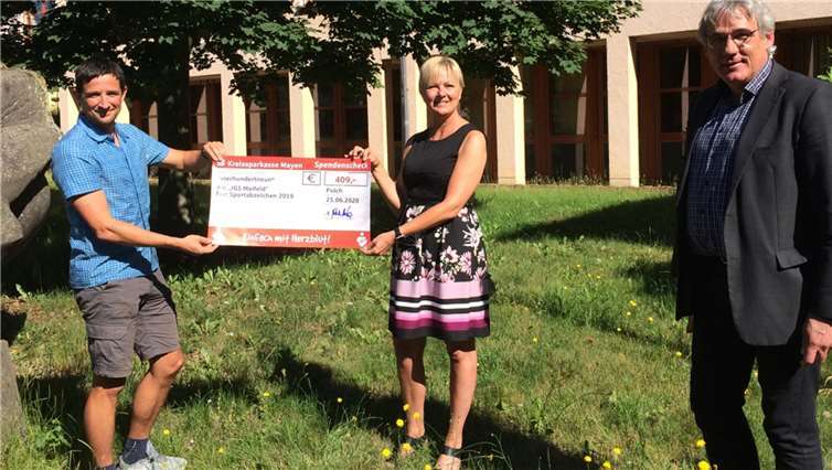 Da die ursprünglich vorgesehene Spendengala bedingt durch Corona ausfallen musste, übergab KSK-Beraterin Bianca Ackermann-Reichert (Mitte) den symbolischen Spendenscheck - noch rechtzeitig vor den Schulferien - am Schulgebäude der IGS Maifeld an Schulleiter Malte Möbius (rechts) und den verantwortlichen Sportlehrer Thomas Strotzer. Beide bedankten sich im Nahmen der Schule und empfanden die Spende als besondere Wertschätzung ihrer täglichen Arbeit und versprachen, dass die finanzielle Unterstützung in sportlichen Projekten der Schule ihre Verwendung finden wird.
