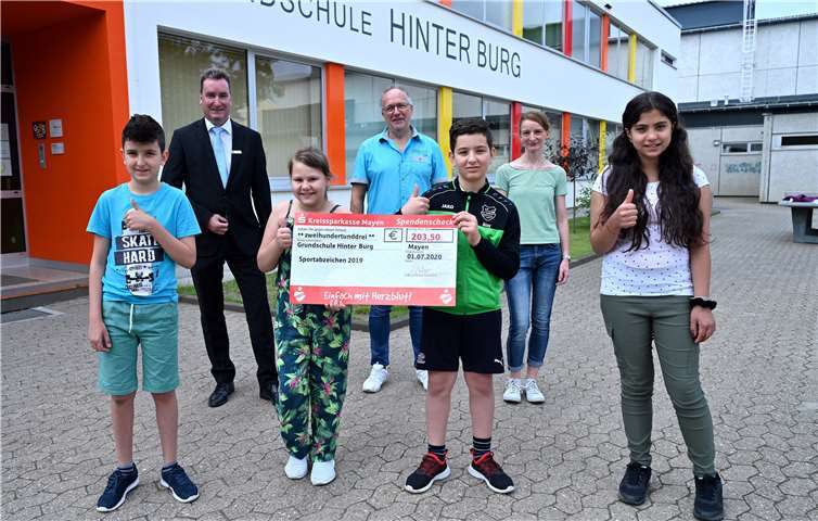 Da die ursprünglich vorgesehene Spendengala bedingt durch Corona ausfallen musste, übergab KSK-Filialleiter Klaus Wermes (2.v.l.) den symbolischen Spendenscheck an Schulleiter Christoph Buschmann (3.v.l) und die verantwortliche Sportlehrerin Rita Laux 2.v.r.). Beide bedankten sich im Namen der Schule und empfanden die Spende als besondere Wertschätzung ihrer täglichen Arbeit. Die Schüler (vorne v.l.) Almir Jasaragic, Amalia Popa, Alla Alay und Juudy Mohwa freuen sich stellvertretend für ihre Mitschüler über den „großen“ Scheck. Foto: KSK