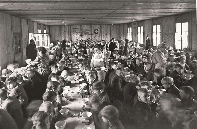 Das Foto aus der Festschrift zeigt Koblenzer Schulkinder beim Mittagessen in der Baracke der „Schweizer Spende“ auf dem Clemensplatz 1946. Der Caritasverband half bei der Organisation und Verteilung von Hilfsgüter. Karl Stiebel