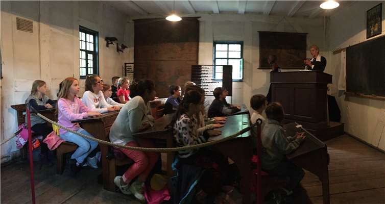 Das „Fräulein Lehrerin“ steht erhöht an ihrem Katheder und erzählt vom Kaiser. Die Kinder hören gebannt zu. Fotos: privat