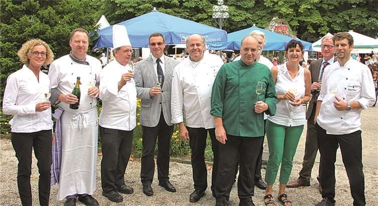 Das Köcheteam um Zwei-Sterne-Koch Hans Stefan Steinheuer (5.v.l.) hat MdL Horst Gies (4.v.l.) und Bürgermeister Guido Orthen (2.v.r.) zum Foto mit in seine Mitte genommen. -BÜN-
