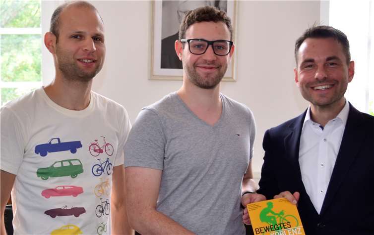 Das Programmheft zum Fahrradtag überreichten David Schüler (v.li.) und Dennis Feldmann dem Koblenzer OB David Langner. -HEP-