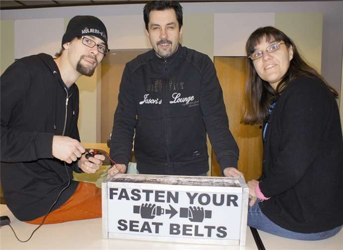 Das Schild „Fasten your seat belts“ (Bitte anschnallen) spielt in der Komödie eine ganz besondere Rolle (v.l.) Alexander Mäurer, André Ternes und Regisseurin Claudia Palm. Privat