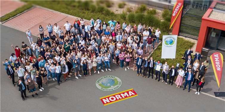 Daumen hoch für eine nachhaltige Zukunft: NORMA-Mitarbeitende und die Geschäftsleitung versammelten sich zur Übergabe des Zertifikats von GREEN BRAND vor dem Unternehmenssitz in Fürth.Foto: NORMA