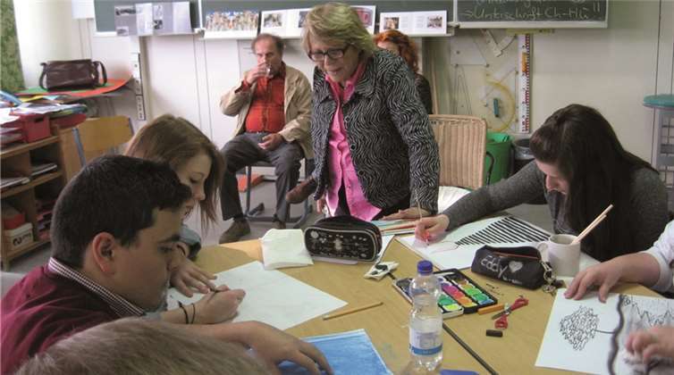Den Schülern steht Sara Atzmon beratend zur Seite, während diese ihre Bilder malen.