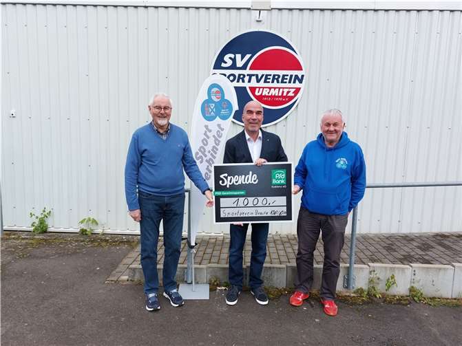 Den entsprechenden Scheck nahmen der Schatzmeister Edgar Becht (li.) sowie der Vereinsmanager Klaus Höfer (re.) vom Vorstand der Bank, Björn Engelmann, mit einem Dank entgegen. Quelle: SV Urmitz