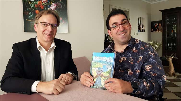 Der 34-jährige Stefan Zeidan (rechts) gemeinsam mit Heimatbuch-Autor Horst Hohn (links) und der aktuellen Ausgabe des Heimatbuches 2023 des Landkreises Mayen-Koblenz. Foto: privat