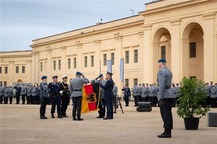Der Befehlshaber des Unterstützungskommandos der Bundeswehr befestigt das Fahnenband des Kommandos Gesundheitsversorgung an der Truppenfahne. Foto: Bundeswehr/Helmut von Scheven