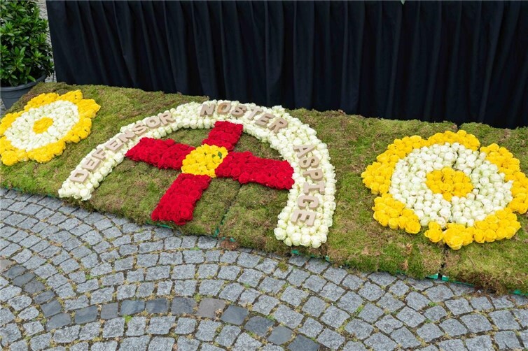 Der Blumenschmuck vor der Altarbühne mit den Worten „Defensor Noster Aspice“ wurde aufwändig aus roten, weißen und gelben Rosenblüten gestaltet. 