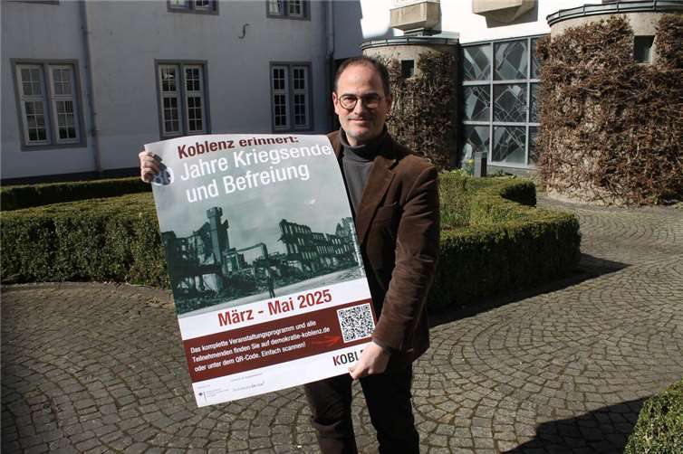 Koblenz erinnert an 80 Jahre Kriegsende und Befreiung Der Dezernent für Bildung und Kultur Ingo Schneider mit dem Veranstaltungsplakat. Foto:Stadt Koblenz/T. Knaak