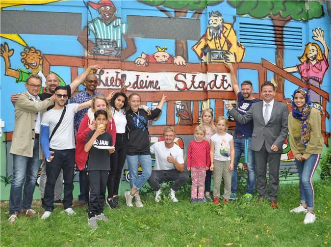 Der Erste Beigeordnete Holger Jung (2.v.r) und Andreas Jung (links), Leiter des städtischen Fachbereichs Jugendhilfe, sind begeistert von dem Kunstwerk. Gemeinsam mit den kleinen und großen Künstler präsentieren sie das Ergebnis der Graffiti-Aktion, an dessen Umsetzung Dennis Diedrich (2.v.l.) maßgeblich beteiligt war. Foto: Stadt Meckenheim