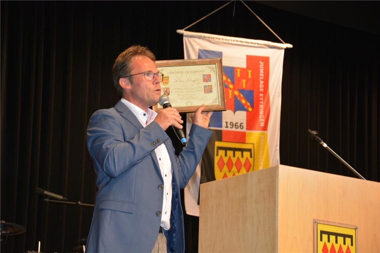 Der Ettringer Bürgermeister Alexander Weber präsentiert die Partnerschaftsurkund...