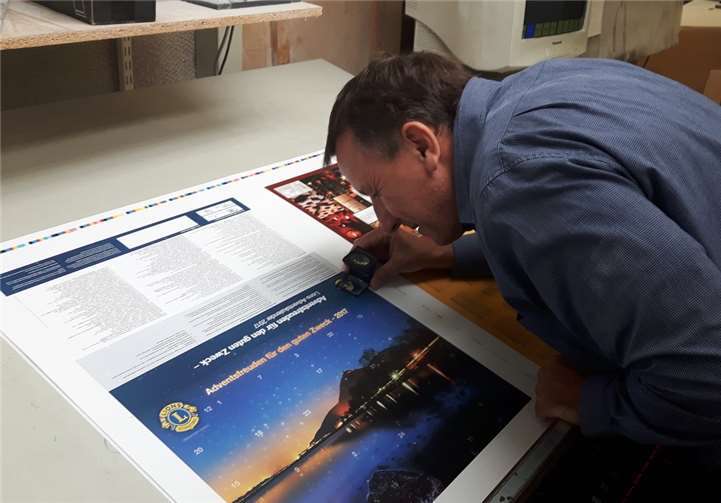 Der Kalenderbogen wird von einem Mitarbeiter kontrolliert, bevor der Druck startet. LC Remagen