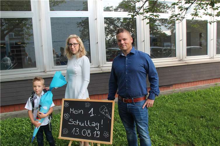 Der „Klassiker“ für das Fotoalbum: Der 6-jährige Erstklässler Adrian und seine Eltern posieren am Eingang der Lindenschule vor der Tafel „Mein erster Schultag“.