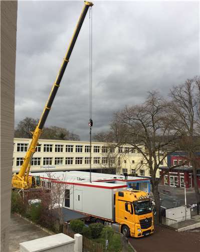 Der Kran hebt ein Container-Modul vom LKW.