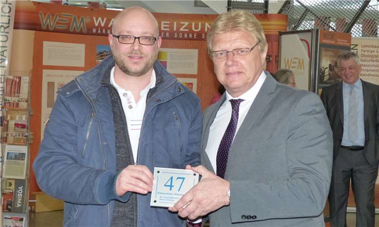 Der Kreisbeigeordnete Rolf Schäfer (rechts) überreichte Bauherr Marcel Wagner-Petrich die Klimaschutzhausnummer