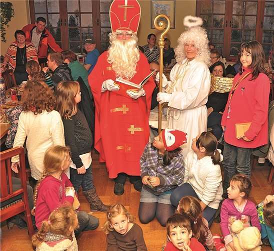 Der Nikolaus, begleitet von seinem Engelchen, hatte vieles zu berichten und gespannt hörten die Kleinen zu seinen Füßen zu. W. Mies