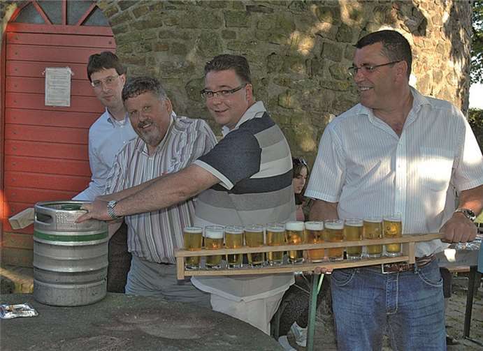 Der Ortsvertretungsvorsitzende Joachim Heinrich (l.) und der Ortsausschussvorsitzende Karl-Josef Wachenberg (2. v. l.) schlagen das offizielle Mühlenfestfass an. Weigert