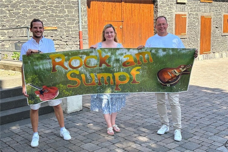 Der Platz an der Thürer Dorfscheune wird am 22. August zum „Rock am Sumpf“-Ground. Ortsbürgermeister Lukas Ellerich (links), Laura Berresheim und Jörg Lempertz, Schirmherr und Bürgermeister VG Mendig, rühren schon einmal die Werbetrommel.