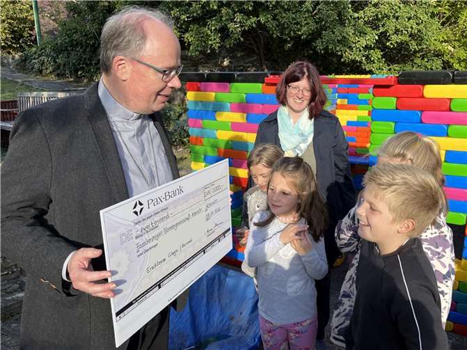 Der Trierer Bischof Dr. Stephan Ackermann erklärt den Kindern in Altenahr, woher die Spende kommt. Gemeindereferentin Manuela Kremer-Breuer freut sich, dass sie durch das Geld weitere XXL-Bauklötze für unterschiedliche Aktionen kaufen konnte.  Foto: Bistum Trier/Julia Fröder