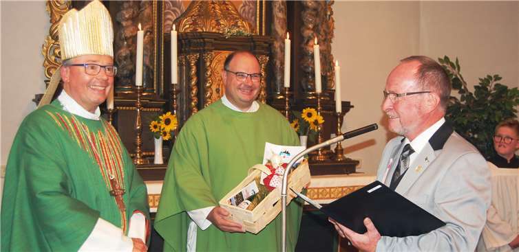 Der Trimbser Ortsbürgermeister Peter Schmitt (rechts) bedankte sich beim Trierer Bischof Stephan Ackermann (links) für dessen Besuch. Derweil hielt Pfarrer Jörg Schuh aus Ochtendung die Geschenke fest.