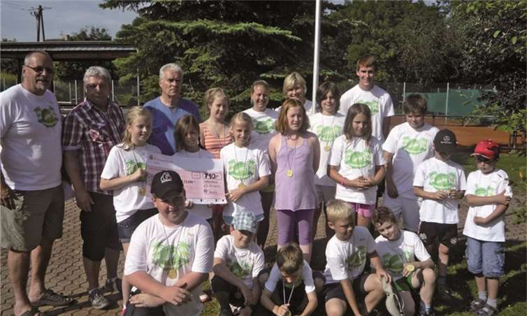 Der Vorsitzende der TCO Klaus Jansen, der Vorsitzende des Fördervereins Heinz Dieter Stein, Helge Fiedler (v.li.) und viele CampKids bei der Scheckübergabe. privat