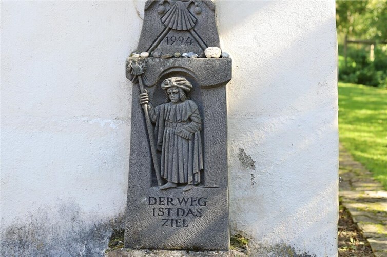 „Der Weg ist das Ziel“: Stele mit dem Heiligen Jodokus in Pilgerkleidung an der Kapelle St. Jost.