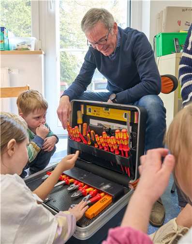 Der Werkzeugkoffer von Norbert Rausch hatte es den Kindern besonders angetan. Sie löcherten ihn mit Fragen, welches Teil man für welche Arbeit braucht.  Foto: Sascha Ditscher/evm