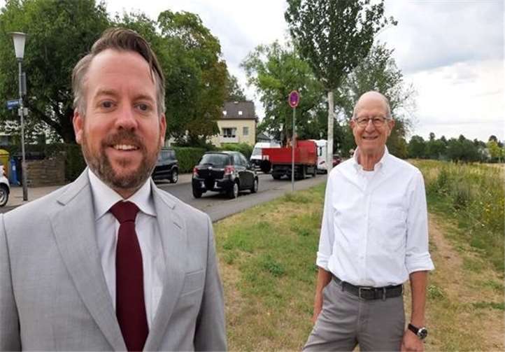 „Der breite Weg im grünen Gelände auf der Südseite der Rüsternallee wird heute schon von vielen Fußgängern gern genutzt. Man kann ihn wie einen Feldweg befestigen. Der asphaltierte Bürgersteig zusammen mit dem „studentischen“ Parkraum (beides links im Bild) könnte dann zur Errichtung eines Radwegs eingesetzt werden.“ Das ist die Idee von den Karthäusern Stephan Wefelscheid (links) und Edgar Kühlenthal (rechts), beide Stadträte von den Freien Wählern. Fotos: Freie Wähler