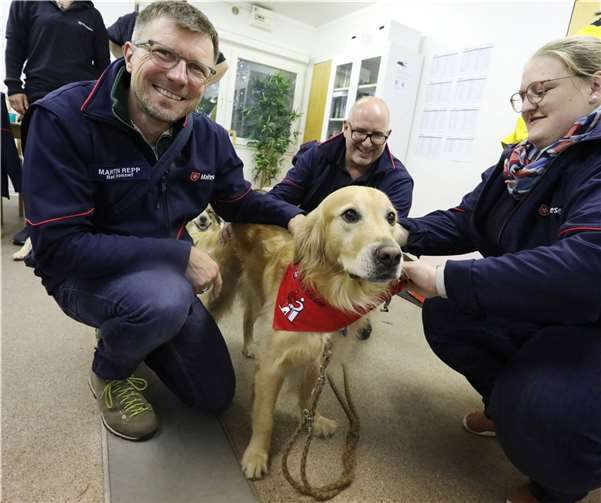 Der große Ben hat bereits Besuchsdienst-Erfahrung. Unter den Augen des stolzen Herrchens Martin Repp (li.) erhält er sein Malteser-Halstuch von Carina Frings. Andreas Archut (Mitte) darf streicheln. 