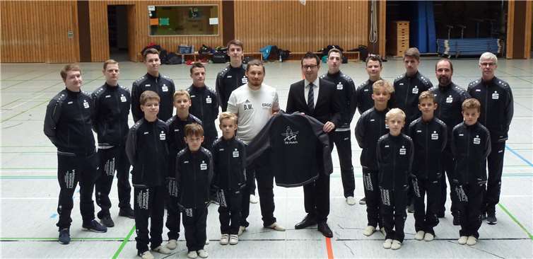 Der stellvertretende Filialleiter Herr Steinsieg und Übungsleiter Daniel Wagenleitner übergaben die neuen Anzüge an die Turner.  R. Schlich