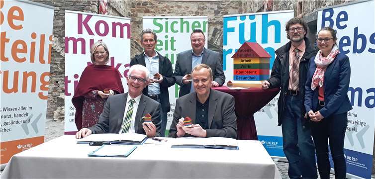 Der stellvertretende Generaldirektor der GDKE, Dr. Dr. Axel von Berg (vorne links) und Manfred Breitbach, Geschäftsführer der Unfallkasse, besiegeln das BGM-Vorhaben im Beisein von (von links) Anja Schuch (BGM-Ansprechpartnerin/Projektleitung), Manfred Neumann (Personalrat/Sicherheitsbeauftragter), Ulrich Sabel (Personalratsvorsitzender), Dr. Rainer Radtke (UK RLP), Wenke Simon (UK RLP).privat