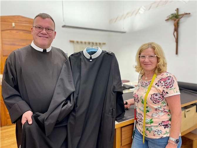 Der stellvertretende Generalsuperior der Franziskanerbrüder vom Heiligen Kreuz, Bruder Bonifatius Faulhaber und Lucie Fulsche mit einem neuen Habit aus der Hausener Brüderschneiderei in Hausen/Wied. Quelle: Franziskanerbrüder vom Heiligen Kreuz e. V.