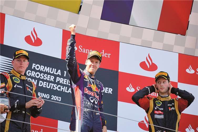 Der strahlende Sieger des Rennens Sebastian Vettel (Mitte) auf dem Podium, eingerahmt von den beiden platzierten Lotus-Piloten, Kimi Räikkönen (links) und Romain Grosjean.