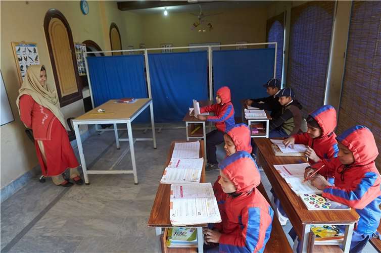 Die 2. Klasse im Unterricht. Da es morgens im Winter noch kühl ist und die Klassenräume nicht beheizt sind trugen die Kinder ihre vom Verein gekauften rot-blauen Jacken mit Kapuze. Thomas Frey