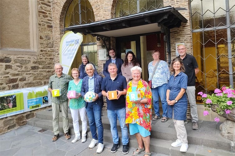Die Aktiven der Fairtrade-Stadt Sinzig mit interessierten Besucherinnen und Besuchern zur Ausstellungseröffnung der Fairen Woche 2026 vor dem Schloss Sinzig