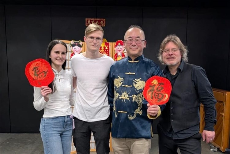 Die Band Reflexum posierte mit dem Organisator, Herrn Guo, für ein Foto. Die beiden Schriftzeichen, die sie hielten, stammten von Herrn Guo: „福“ (Glück) und „马“ (Pferd). Beide Zeichen enthielten das Bild eines Pferdes.